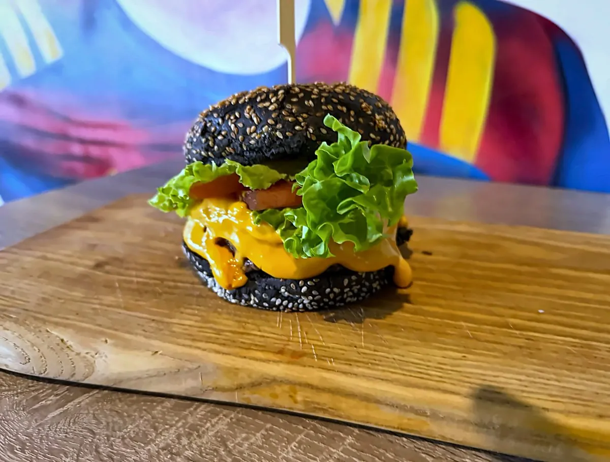 Un burger au pain noir, cheddar fondu, servi sur une planche