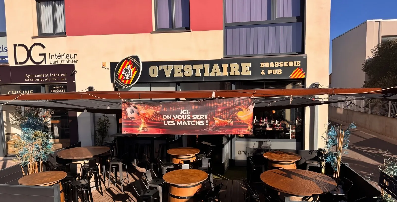La façade d’O’Vestiaire, rue des Grillons : l’enseigne, la banderole « Ici, on vous sert les matchs ! » et la terrasse